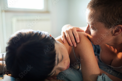 Loving lesbian couple cuddling in bed photo