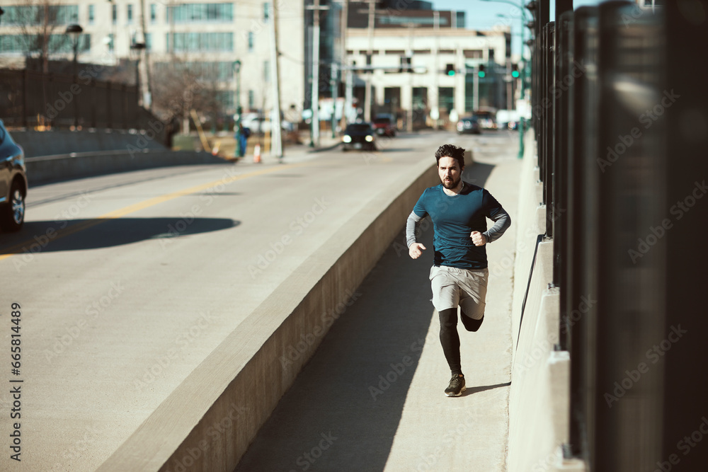 Young fit man running across the bridge