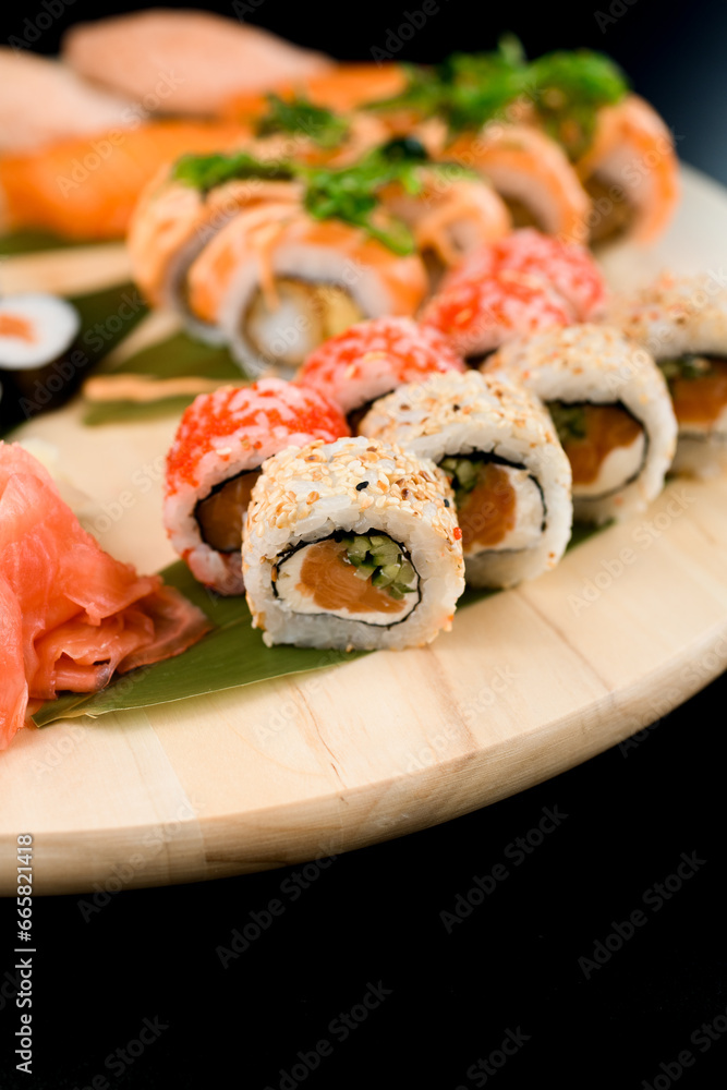 Assorted sushi rolls on a round wooden board, side view Assorted sushi rolls on a round wooden board, side view