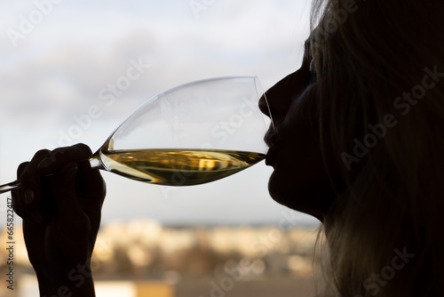Woman drinking white wine, silhouette with glass