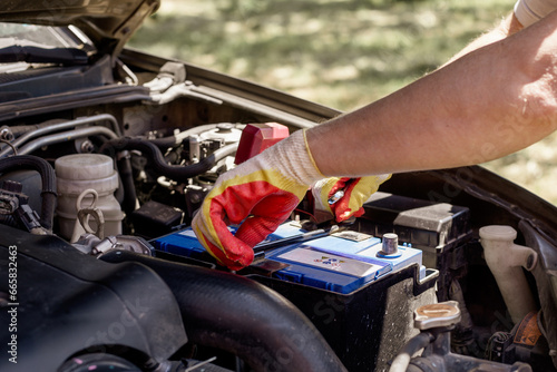 car mechanic repairs a car. A mechanic removes a car battery