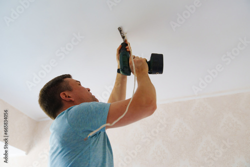 A man is working on the installation of a ceiling luminaire on the ceiling.
