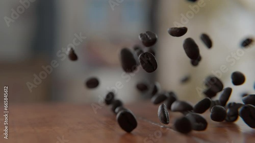 Coffee beans falling on and bouncing off of the wooden table