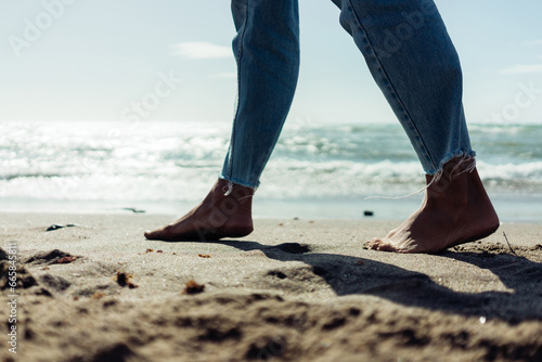 Close-up of female bare feet on the sand by the seashore. © sutulastock