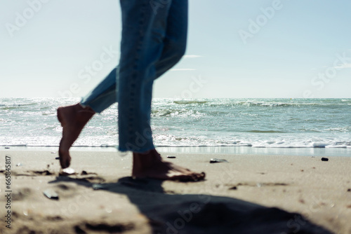 Close-up of female bare feet on the sand by the seashore. © sutulastock