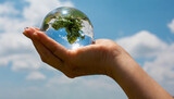earth crystal glass globe ball and growing tree in human hand