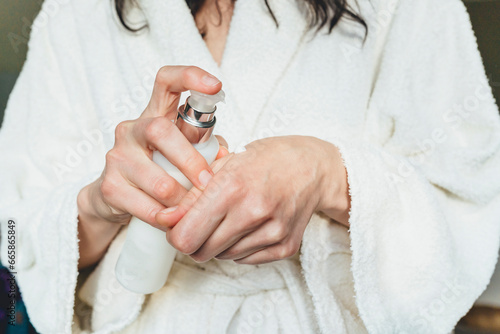 Close up view of woman dropping moisturizing serum on her hand. Selective focus on bottle with dispenser in woman hands. Beauty therapy  skincare concept. Beauty and wellness concept