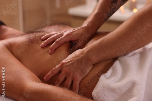 Man receiving professional belly massage in spa salon, closeup