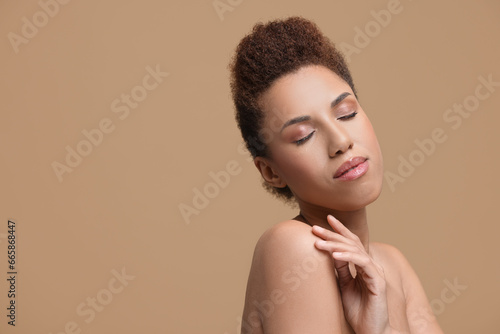 Portrait of beautiful young woman with glamorous makeup on light brown background. Space for text