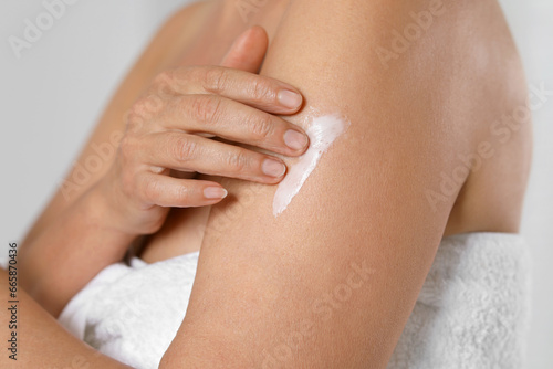 Fototapeta Naklejka Na Ścianę i Meble -  Woman applying body cream onto arm on grey background, closeup