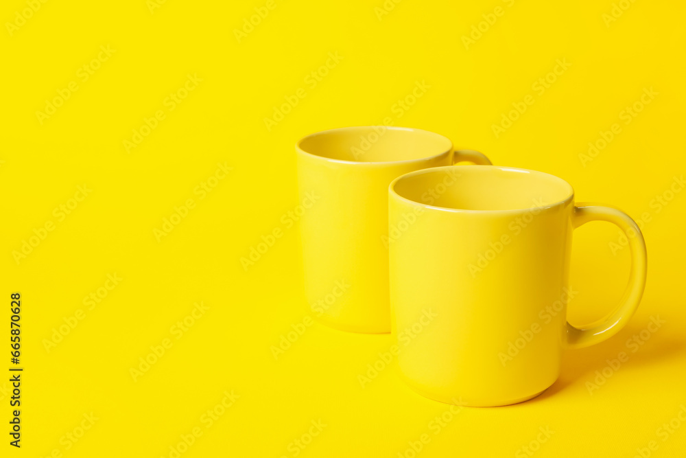 Two ceramic mugs on yellow background, space for text Two ceramic mugs on yellow background, space for text