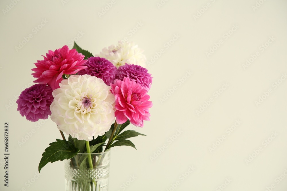Bouquet of beautiful Dahlia flowers near white wall, space for text
