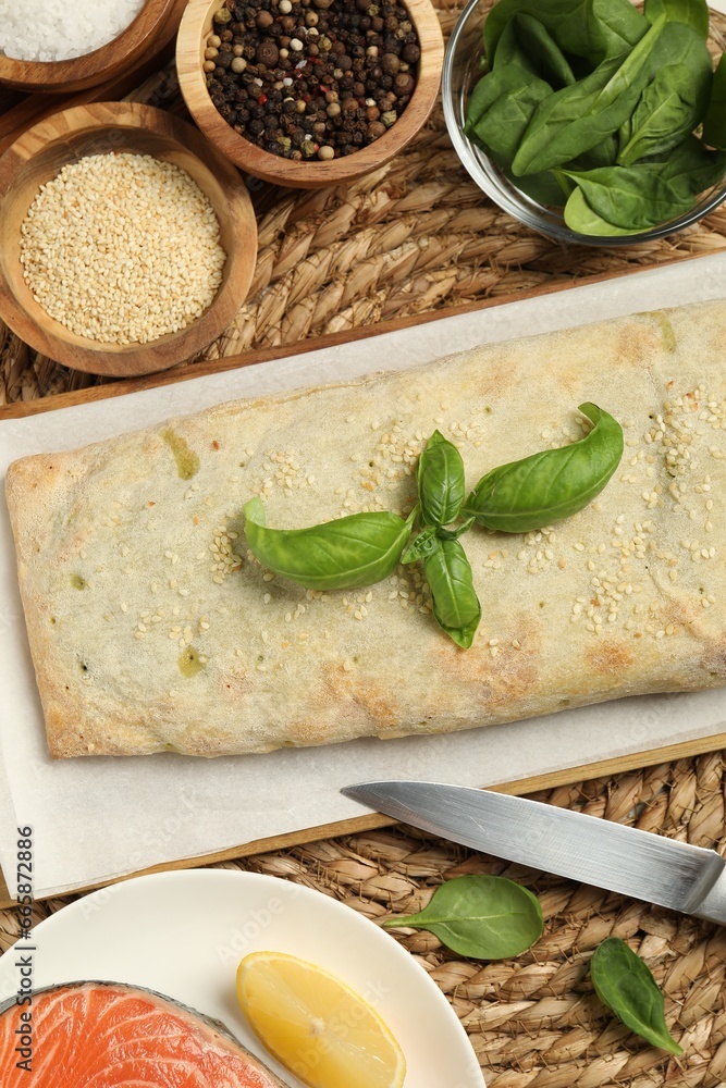 Delicious strudel with tasty filling and basil served on wicker mat, flat lay Delicious strudel with tasty filling and basil served on wicker mat, flat lay