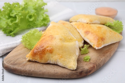 Delicious samosas and lettuce on white table, closeup