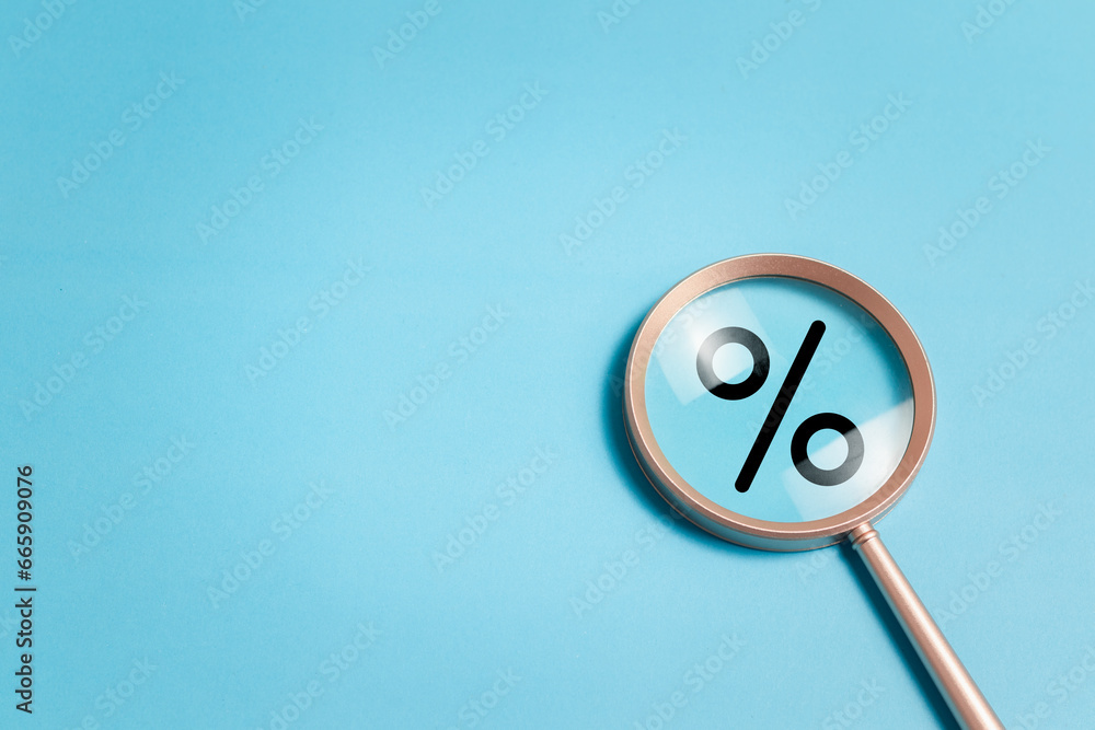 Φωτογραφία Magnifying glass focuses on percentage symbol on blue background for Interest rate financial and mortgage rates concept