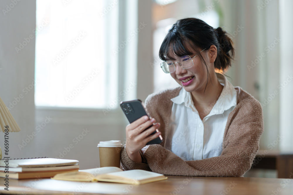 Positive asian young female accountant using a smartphone at her office desk. Woman relaxing on her mobile application. Positive asian young female accountant using a smartphone at her office desk. Woman relaxing on her mobile application.
