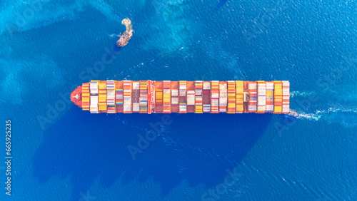 Top view Container ship full capacity approaching the port by A tugboat is pulling International Container ship loading, unloading at sea port, Transportation, Shipping, Logistics, import export
