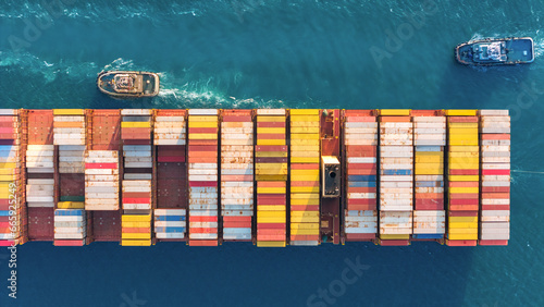 Top view Container ship full capacity approaching the port by A tugboat is pulling  International Container ship loading, unloading at sea port, Transportation, Shipping, Logistics, import export photo