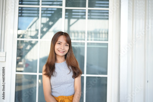 Happy Asian female tourist next to accommodation building during sunset