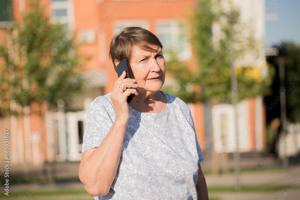 A cheerful elderly woman is talking on a smartphone