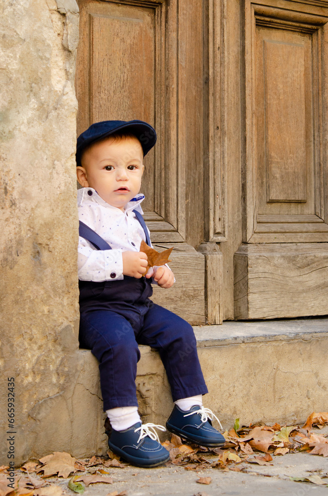 Beautiful boy sitting on a portal of old house