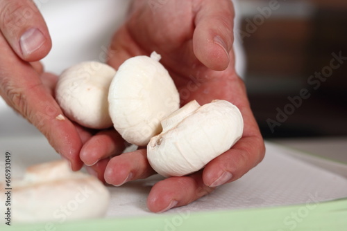 Chef holds button mushrooms in hand. Making Chicken, Cheese and Leek Parcel Series. © ffolas