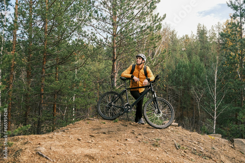 active lifestyle.A cyclist in equipment with a backpack is leaning on a bicycle on a mountain and looking at the landscape.Mountain Bike