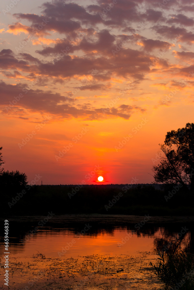 Colorful orange-red sunset over the river surface, vertical view