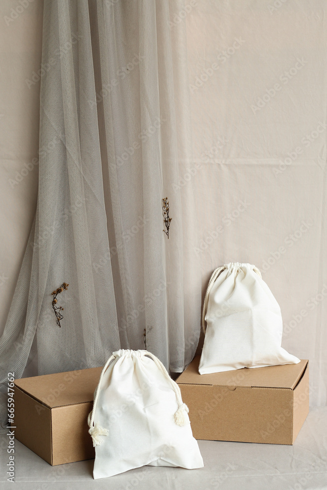 The small drawstring bag and corrugated box are on a pastel color fabric background. The small drawstring bag and corrugated box are on a pastel color fabric background.