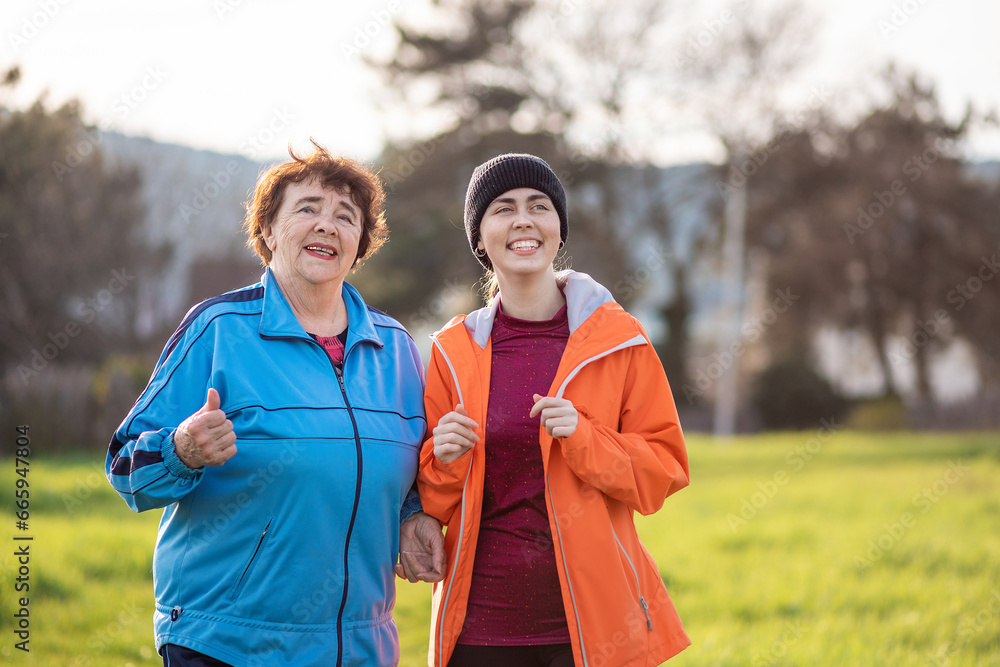 Portrait of happy mature and young women walking down the park. Spring time. International Day of Older Persons Portrait of happy mature and young women walking down the park. Spring time. International Day of Older Persons
