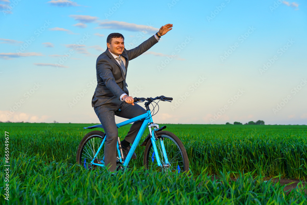 businessman rides a bicycle through a green grass field, the concept of activity, leisure or freelancing businessman rides a bicycle through a green grass field, the concept of activity, leisure or freelancing