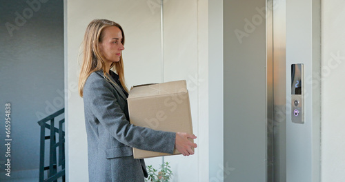 Happy woman with cardboard box coming out from elevator