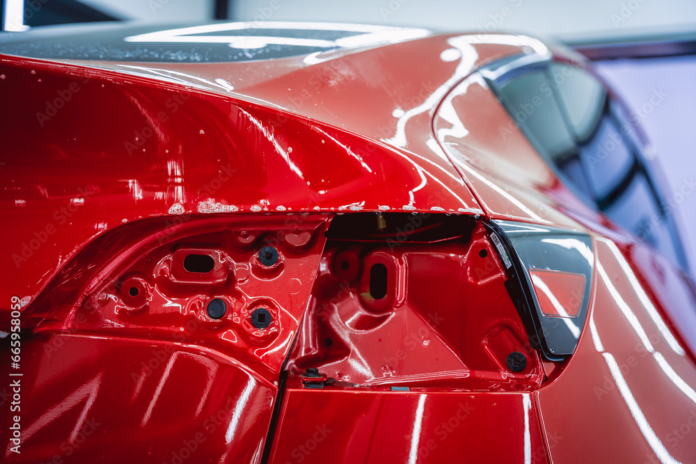 The process of installing protective film on the new red car. The process of installing protective film on the new red car.