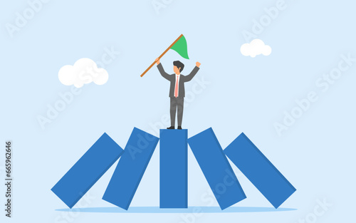 Winner takes all concept. Business competition leaves only the strongest. Strength to survive in business crisis. A businessman standing between upright domino among falling dominoes