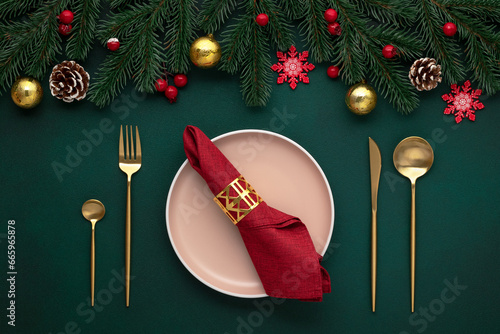 Empty plate, golden cutlery. Festive table setting, christmas decorations. Celebration xmas eve: flat arrangement. Red, gold accent. Shiny baubles, fir cones, evergreen tree. Holiday banquet, top view