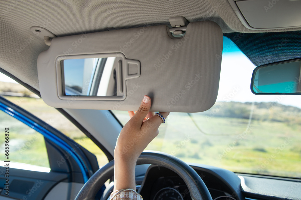 Female hand adjusting sun visor in a car.