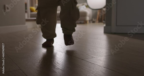 Legs of toddler walking around house. Baby confidently skillfully walks around house showing mom new skills. Baby learns to walk, makes progress, walks confidently for first time, takes first steps