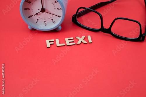 Concept of flexible time. The letter FLEXI on the red background with an alarm clock and eyeglasses. Copy space for text, message, information, etc. photo