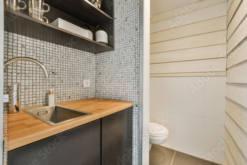 a kitchen with wood counter tops and white tiles on the wall behind it is a sink, fauced by an open shelf photo