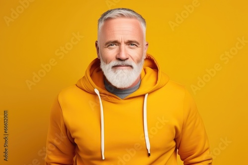 Middle-aged Caucasian man in yellow sweatshirt on ywllow background smiling, cheerful and pleasant. © Eva Corbella