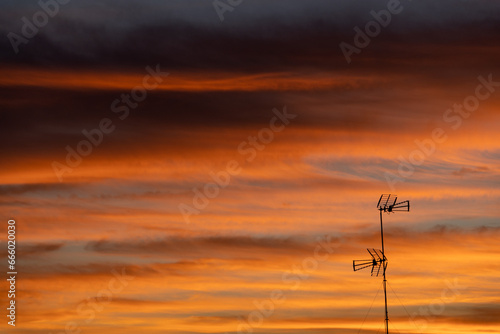 a sunset cloudscape image filled with golden clouds and a single television antenna silhouette.