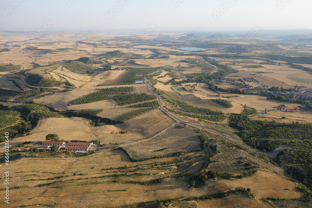 Obraz premium Vue surplombante sur un paysage rural aride avec des cultures, des bois et un lac (Espagne)