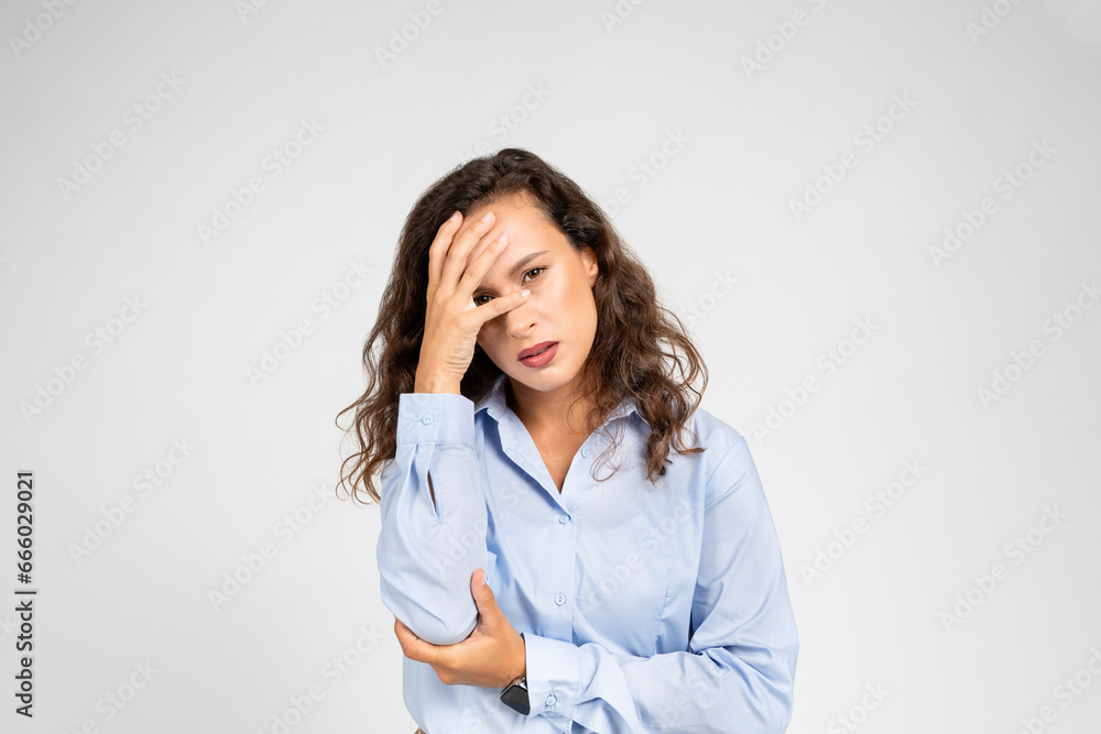 Young stressed woman at work, pressing hand to forehead, evident headache and work stress Young stressed woman at work, pressing hand to forehead, evident headache and work stress