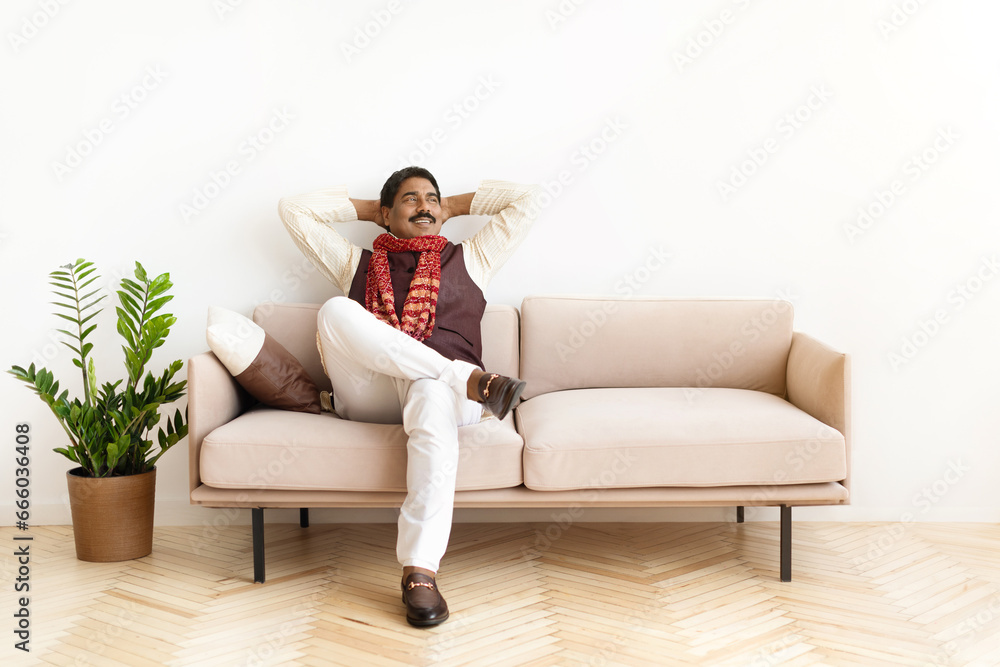 Smiling mature indian man in traditional clothes relaxing at home