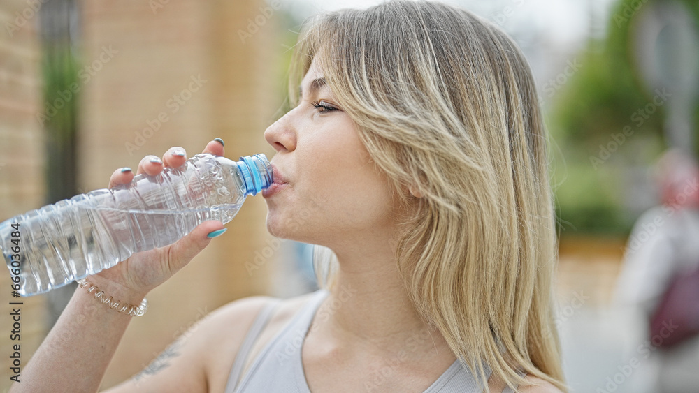 Young blonde woman drinking water at street Young blonde woman drinking water at street