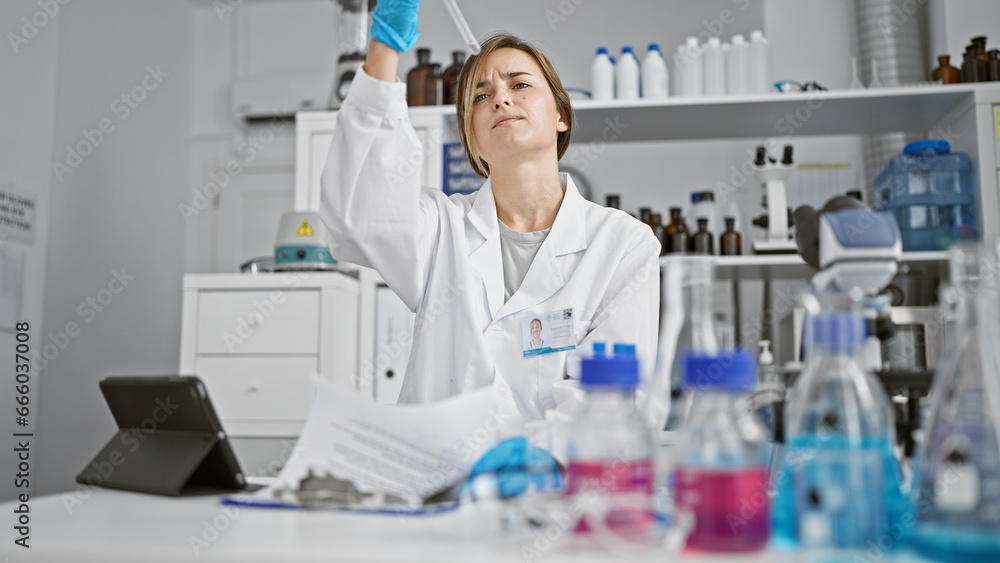 Attractive young blonde woman scientist, immersed in vital medical research, meticulously measuring liquid in a test tube, wrapped in the safety of her gloves, in the bustling heart of a laboratory Attractive young blonde woman scientist, immersed in vital medical research, meticulously measuring liquid in a test tube, wrapped in the safety of her gloves, in the bustling heart of a laboratory