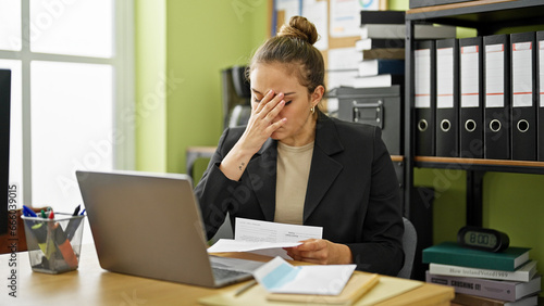 Young beautiful hispanic woman business worker reading letter with worried expression at office © Krakenimages.com