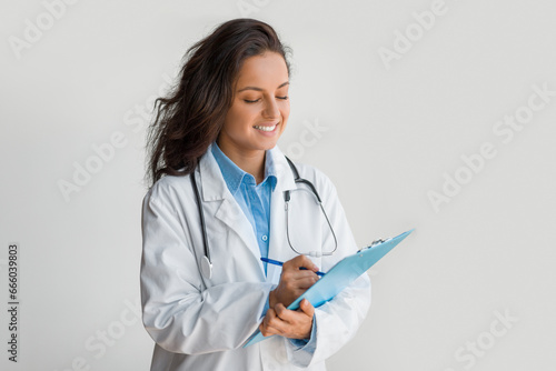 Doctor reviewing notes on clipboard, smiling gently