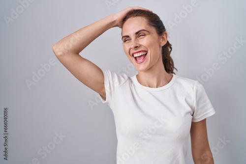 Beautiful brunette woman standing over isolated background smiling confident touching hair with hand up gesture, posing attractive and fashionable