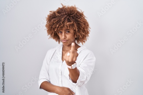 Young hispanic woman with curly hair standing over white background showing middle finger, impolite and rude fuck off expression photo